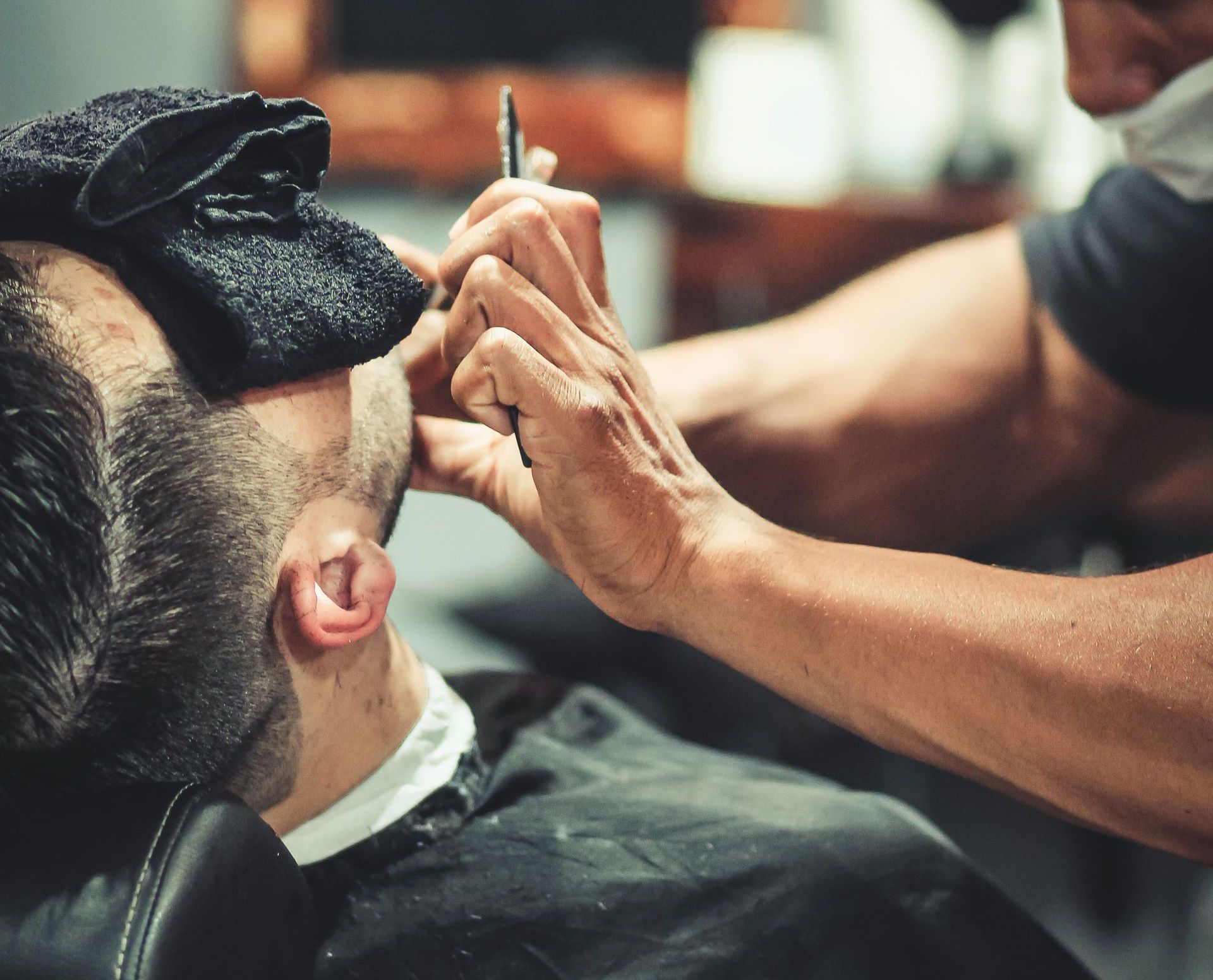 Barber skillfully trims client's beard in a modern barbershop setting.