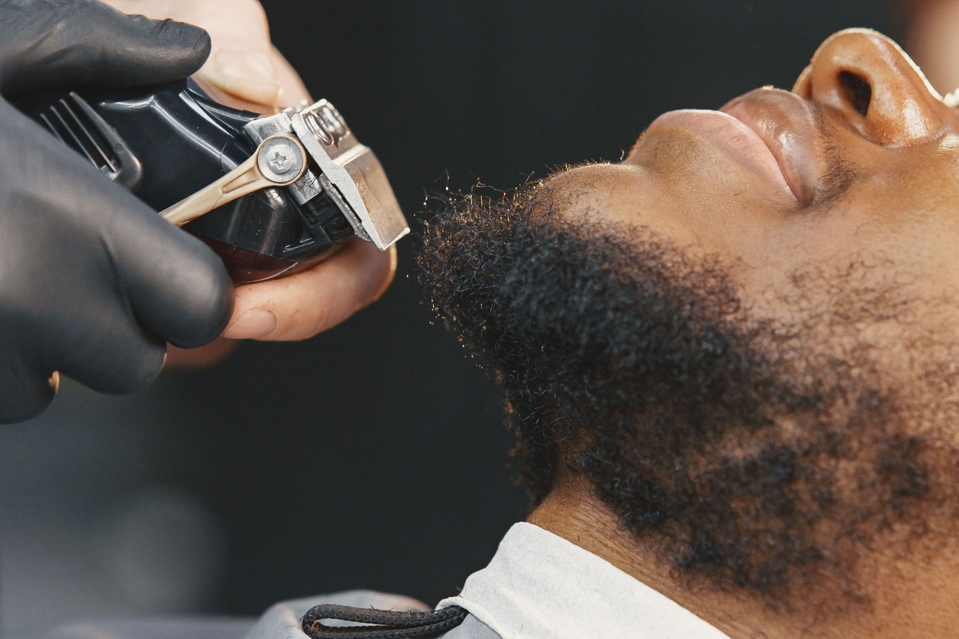 A detailed close-up of a barber trimming a beard, showcasing grooming techniques.