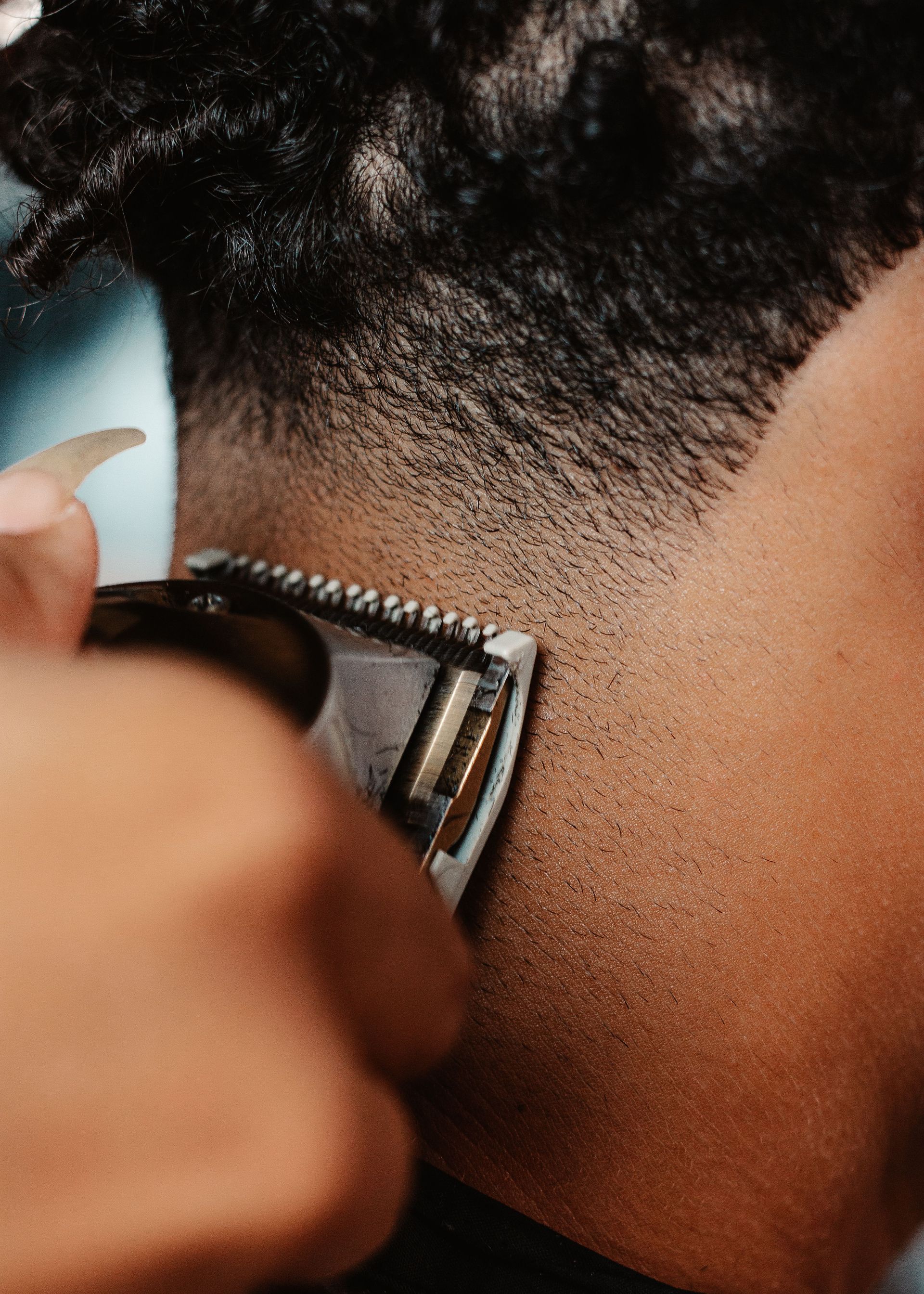A detailed close-up of hair clippers shaving a person's back of the head, showcasing the art of haircutting.